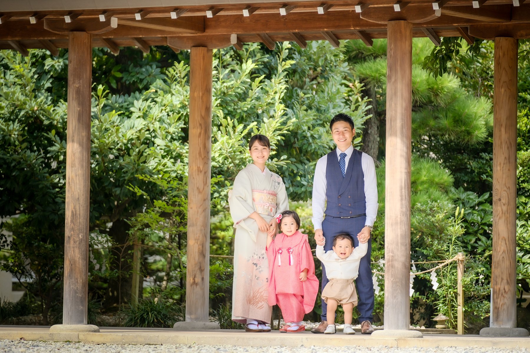 神社の門の下に佇む七五三のご家族